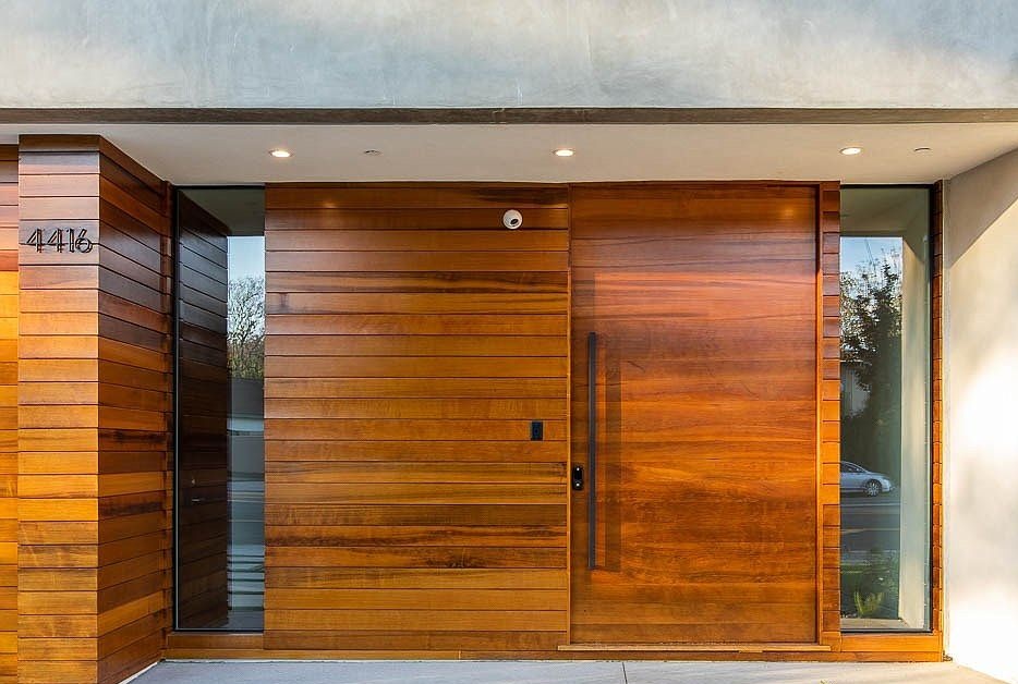 Modern entry with horizontal wood cladding and large pivot-style front door with sidelights.