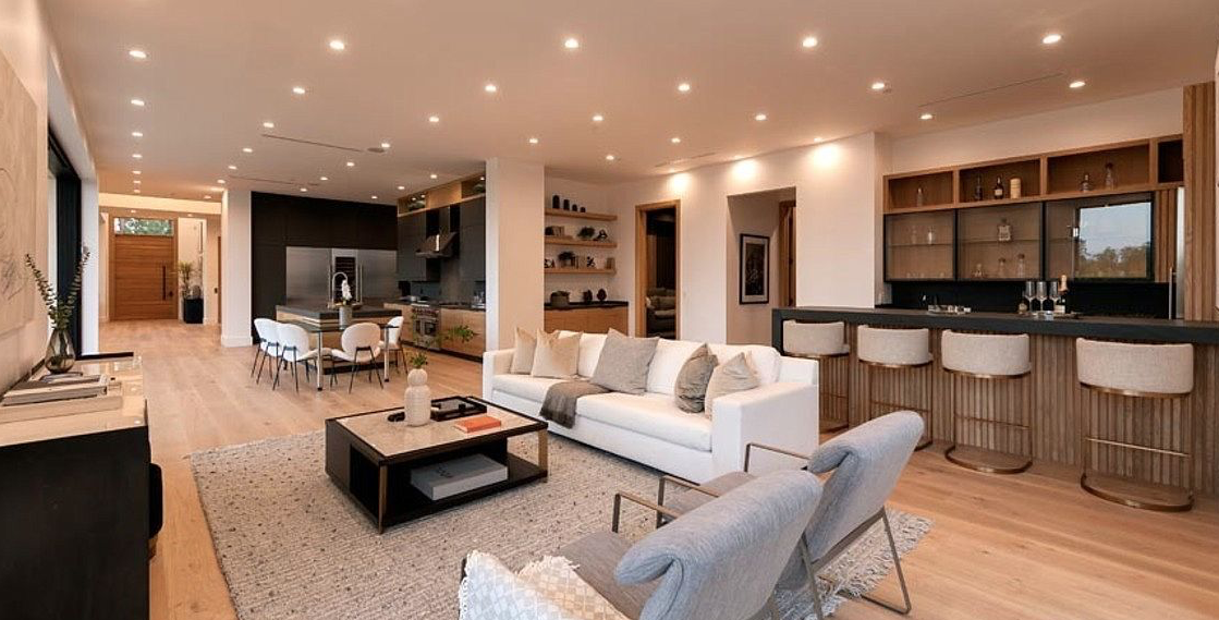 Open living room with white sofa, bar seating, and view into the kitchen and dining area.